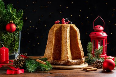 Geleneksel İtalyan Noel pastası Pandoro ve ahşap masa üzerinde Noel süsü, Noel ağacı dalları, arka planda ışıklar. Sihirli Noel gecesi konsepti