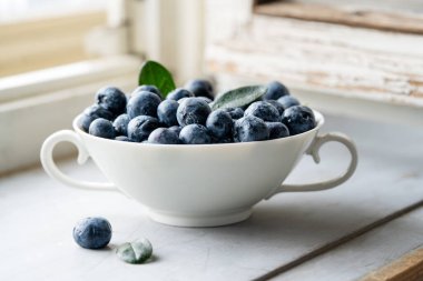 Beyaz çay fincanında yaban mersini, kırsal tarzda, yakın plan, ahşap pencere pervazı. Yüksek kalite fotoğraf