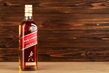 Ternopil, Ukrayna - 19 Nisan 2024: Bir şişe Johnnie Walker Red Label viskisi ahşap arka planda, boş alan ile harmanlanmış viski