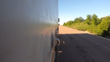 Yaz günü asfalt yolda mal taşıyan bir kamyon. Kamyon kargo karavanının yan tarafı kırsalda hareket ediyor. Endüstriyel araba hedefe gidiyor. Lojistik ve ulaşım kavramı