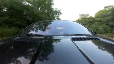 Kırsalda arabayla giden genç bir çiftin ön görüntüsü. Erkek arkadaş ve kız arkadaş yaz akşamında yolculuğun tadını çıkarıyor. Seyahat ya da aile kavramı. Kapat..