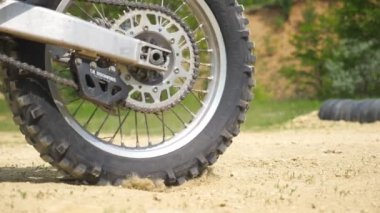 Güçlü off-road motorsikletinin tekerini kapat. Hareket başlat ve kuru zemini veya tozu tekmele. Motokros motoru hareket etmeye başlıyor. Motor sporu ya da aktif yaşam tarzı kavramı. Yavaş çekim kenar görünümü.