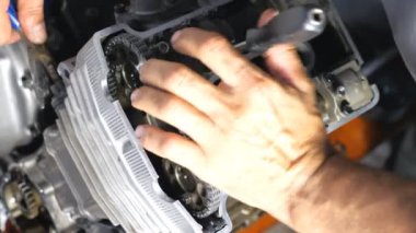 Parçalanmış motosiklet motorunun en üst görüntüsü. Profesyonel tamirci, aracı kullanarak motoru tamir ediyor. Tamirci garajda ya da atölyede çalışıyor. Arabalara ya da motorsikletlere bakan bir adam. Yavaş çekim. Yakın çekim..