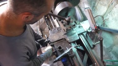 Garajında ya da atölyesinde eski tezgahıyla çalışan tanınmayan bir adam. Tamirci metal işleme için torna kullanıyor. İşe dönüşün görüntüsü. Yavaş çekim. Yakın çekim..