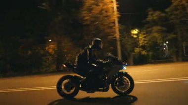 Miğferli genç adam şehir caddesinde modern spor motosikletle hızlı gidiyor. Motosikletli, boş yolda motosikletiyle yarışıyor. Bisikletli adam. Özgürlük ve hobi kavramı. Yan görünüm.