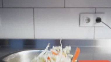 Eldivenin içindeki erkek eli malzemeleri karıştırıyor ve mutfaktaki demir kasede karıştırıyor. Salata için Çin lahanası, mısır, yumurta ve yengeç çubuklarını karıştıran bir şef kolu. Yemek hazırlama kavramı. Kapat..