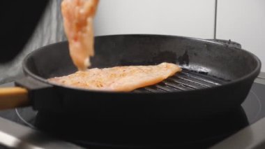 Aşçının erkek eli mutfak restoranında tavuklu fileto yapıyor. Aşçı mutfakta sıcak tavada lezzetli et pişiriyor. Lezzetli yemek yapma süreci. Yemek hazırlama kavramı. Kapat..