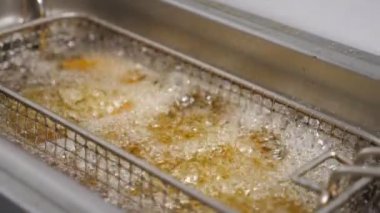 Çıtır patates kızartması mutfakta kızartma yapıyor. Lezzetli patates dilimleri kızgın yağda kızartılıyor. Mutfakta fast food yapma süreci. Yemek hazırlama kavramı. Üst görünüm.