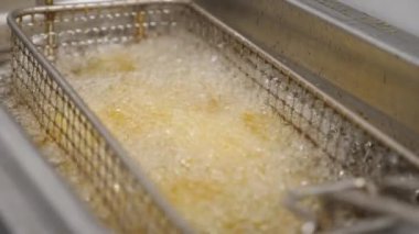 Çıtır patatesler mutfakta kızgın yağda kızartılıyor. Lezzetli patates kızartmaları mutfakta fritöze dönüşüyor. Fast food yapma süreci. Yemek hazırlama kavramı. Üst Görünüm Yavaş Çekim.