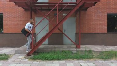 İş adamı bir iş merkezinin merdivenlerinden çıkıyor. Resmi giyinmiş, çantalı, merdivenlerde yürüyen ve telefonla konuşan kendine güvenen bir adam. İşçi ofiste işe gidip geliyor. Başarılı kariyer kavramı.
