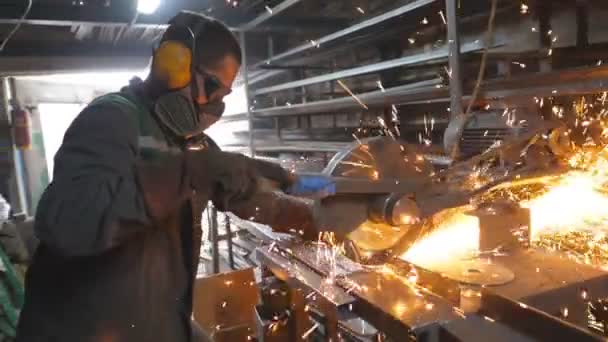 円形のガレージで鋼を見た男 安全保護摩耗の労働者は 金属を切断するために鋸切断機を使用します 金属を研いでる 工業生産 火花が熱い金属から飛ぶ ドリーショット — ストック動画