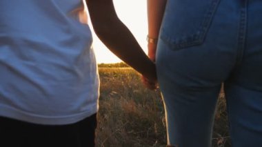 Anne ve kızın kadın elleri gün batımında çimen tarlasında birbirlerine sarılıyorlar. Anne çocuğuyla yaz otlağında yürüyor. Arka planda güzel bir güneş ışığı var. Aile sevgisi kavramı. Kapat..