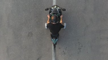 Motosikletlinin lastikleri patlatırken çok duman çıkıyor. Hareket başladığında motosiklet tekeri yolda kayıyor. Spor motosiklet çarkı asfalt yolda dönmeye başlar. Yavaş çekim Havadan çekim.