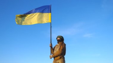 Ukrayna bayrağı sallayan Ukraynalı kadın Ukraynalı asker. Askeri üniformalı ve kasklı bir kadın mavi gökyüzüne bayrak kaldırdı. Rus saldırısına karşı zafer. İstila direnişi kavramı.