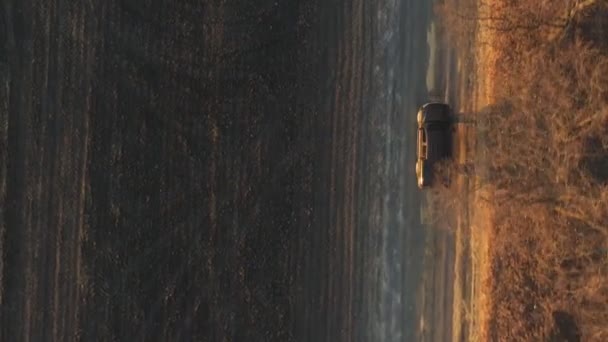 从公路上飞驰而过 沿着农田附近的路线行驶 在耕地附近的乡间小径上驾驶皮卡的空中射击 一辆黑色轿车在犁地附近的道路上行驶 — 图库视频影像