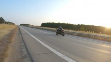 Günbatımında otoyolda hızlı giden bir adamın hava görüntüsü. Motosikletli, kır yolunda motosikletiyle yarışıyor. Yolculuk sırasında bisiklet süren adam. Özgürlük ve macera kavramı.