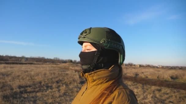 女性のウクライナ軍兵士が戦場を歩いていた 軍の制服を着た女性とヘルメットは日没時に牧草地に行く ロシアの侵略に対するウクライナの勝利 侵入抵抗の概念 スローモーション — ストック動画
