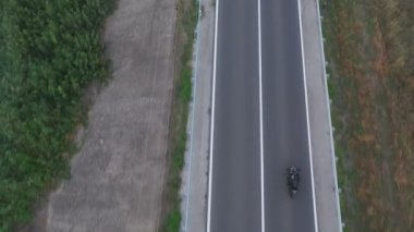 Motosikletli birinin kır yolunda motosikletiyle yarışması. Yolculuk sırasında bisiklet süren bir adam. Havadan bakıldığında, kırsal kesimde motosiklet kullanan bir motosikletli. Özgürlük ve macera kavramı.