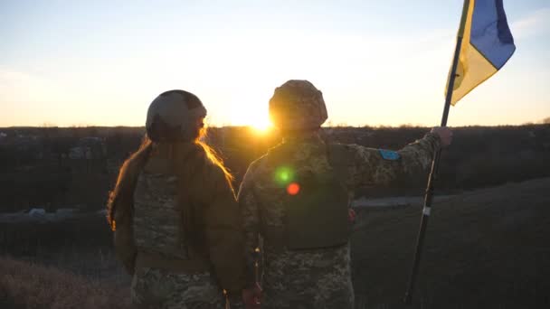 乌克兰军队的士兵在日落的背景下升起乌克兰国旗 身穿军服的人升起了黄蓝色的旗帜 战胜俄国侵略的胜利抵抗入侵的概念 — 图库视频影像