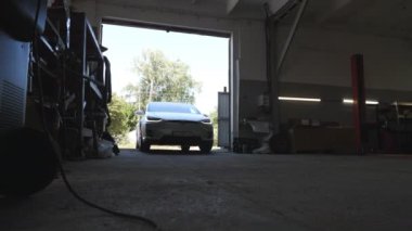 Tamir için garaja giren modern elektrikli arabaları kapatın. Elektrikli SUV aracı atölyeye giriyor. Ulaşım hizmeti kavramı. Yavaş çekim.