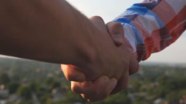 Çatı katında toplantı ve birbirlerini tebrik iki arkadaş. Genç erkekler tokalaşırken üzerinde cityscape arka plan bulanık. Adam açık arasında dostça el sıkışma. Dostluk kavramı. Yavaş hareket kapatmak.