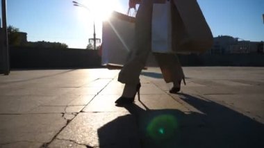 Genç bayan müşteriler alış veriş sonrası alışveriş torbalarını meydanda tutarlar. Modaya uygun bir kadın, şehir caddesinde kağıt paketler taşıyor. Satış ve indirim zamanlarında boş vakit kavramı. Yavaş çekim