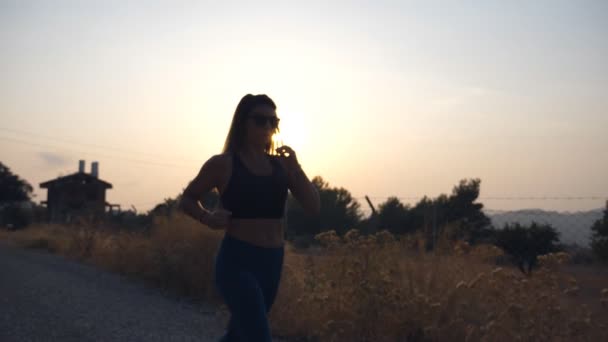 Sportliches Mädchen Joggt Bei Sonnenuntergang Auf Einer Landstraße Junge Frau — Stockvideo
