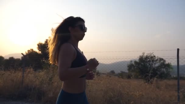 日落时 一个体态魁梧的女孩在乡间小道上慢跑 年轻女人在外面跑健康积极的生活方式 慢动作关闭 — 图库视频影像