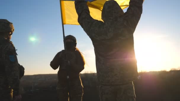 ウクライナ軍の兵士は丘の上に立ち ウクライナの国旗を掲揚した ロシアの侵略に対する勝利の象徴として軍事統一保持手旗の人々 ヨーロッパでの戦争の終結 — ストック動画