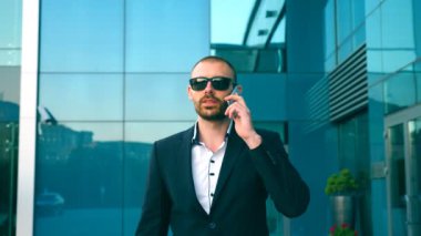 Güneş gözlüklü iş adamının portresi telefonla konuşuyor ve sokakta yürüyor. İşe gidip gelirken iş görüşmesi yapan genç bir adam. Takım elbiseli adam ofis binasına gidiyor.
