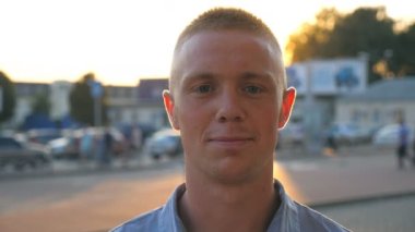 Gömlek ayakta şehir ortamı, yakışıklı başarılı adam portresi yakın çekim içine kamera on sunset Park Arabalar arka planı arıyorum Genç emin iş adamı.