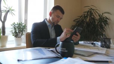 Young entrepreneur analyzing statistical data information on a tablet pc in office. Serious businessman looking at diagrams with statistics on paper while working on digital device. Dolly shot.