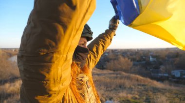 Ukrayna bayrağı sallayan Ukrayna ordusunun kadın askeri. Askeri üniformalı ve kasklı kız sarı-mavi bayrak kaldırdı. Rus saldırısına karşı zafer. İstila direnci konsepti. Yavaşla.