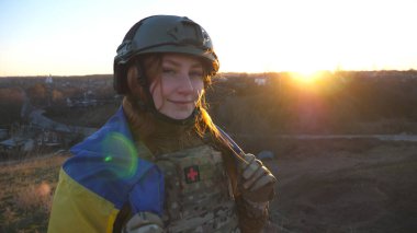 Ukrayna ordusunun mutlu kadın askeri Ukrayna bayrağı sallıyor. Askeri üniformalı kadın Putin 'in ölümüne seviniyor. Kız bayrağı kaldırdı. Rus saldırısına karşı zafer.