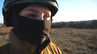 Kadın Ukraynalı askerin profili dışarıda dolaşıyor. Askeri üniformalı ve kasklı bir kadın sahaya çıkıyor. Rus saldırısına karşı Ukrayna 'nın zaferi. İstila direnci konsepti. Yavaş çekim.