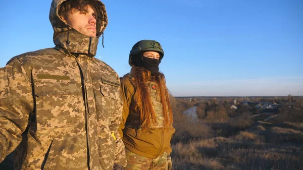People in military uniform sight with hope to the horizon. Male and female ukrainian army soldiers looking into the distance. Waiting for victory against Russian aggression and the end of the war.