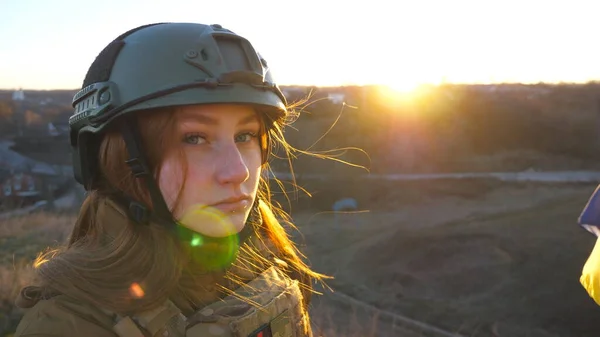 Portrait of young female ukrainian army soldier. Sad emotion on face of girl in military helmet during war in Ukraine. Russian aggression in Europe. Invasion resistance concept. Close up.