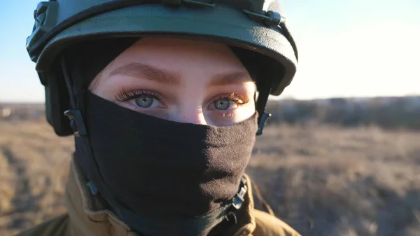 Sight of female ukrainian army soldier in helmet. Portrait of young woman in camouflage uniform confidently looking at camera. Military forces during war. Russian invasion of Ukraine. Close up.