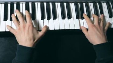 Sentezleyicide oynayan erkek müzisyenin elleri. Mens arms solo müzik ya da yeni melodi çalıyor. Piyanistin parmaklarını piyano tuşlarına yakın tut. Yavaş çekim Üst Görünüm.