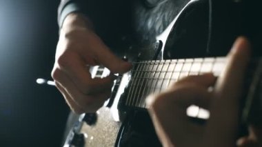 Eller erkek müzisyen elektro gitar çalmak. Mens çalış solo rock müzik silah. Dizeleri, gitarist parmakları kapatın. Stüdyoda güzel siyah arka plan. Ağır çekim yakın çekim.