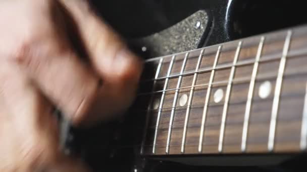 弦を鳴らすギタリストの指を閉じてください エレキギターを弾く男性ミュージシャンの手 成人男性の腕は楽器で演奏します 新しいメロディーを作る男 スローモーション — ストック動画