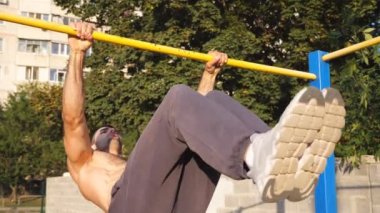 Genç kas sporcusuna yakın yatay bar açıklarında jimnastik numaraları gösteriyor. Spor sahasında spor yaparken statik egzersiz yapan güçlü bir sporcu. Spor yaşam tarzı konsepti.