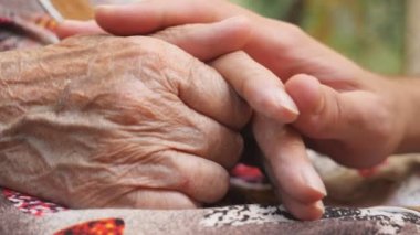 Genç erkek eli yaşlı bir eski kadın açık silah rahatlatıcı kapatın. Torun ve Büyükanne dışarıda birlikte vakit. Bakım ve sevgi kavramı. Yan görünümü ağır çekim.