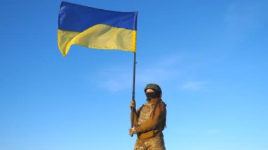 Ukrayna bayrağı sallayan Ukraynalı kadın Ukraynalı asker. Askeri üniformalı ve kasklı bir kadın mavi gökyüzüne bayrak kaldırdı. Rus saldırısına karşı zafer. İstila direnişi kavramı.