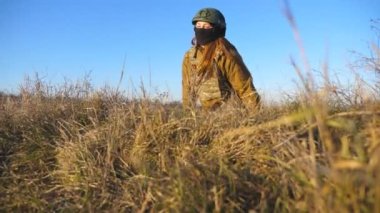 Military soldiers in outfits and helmets leaves from trench after shelling or attack of enemy army. Ukrainian soldiers hides behind a hill from attack and looking out from the shelter. War in Ukraine.