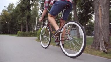Klasik bir bisiklete binen tanınmamış genç adam. Parkta bisiklete binen sporcu çocuk. Sağlıklı aktif yaşam tarzı. Düşük açı. Ağır çekim..