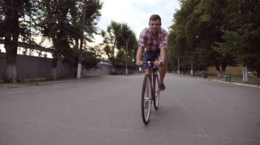 Park road, vintage bir bisiklet sürme genç mutlu adam portresi. Sportif adam Bisiklete binme Açık ve gülümseme. Sağlıklı aktif yaşam tarzı. Önden Görünüm kapatmak yavaş hareket.