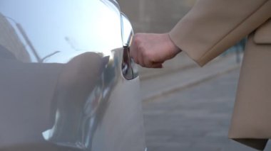 Female hand opening an electric car charging socket cap and plugging in a charger. Woman starting the process of refueling the batteries of her electrical vehicle. Eco friendly auto with zero emission
