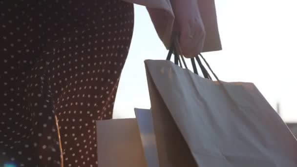 若い女性の手に近い買い物の後に街の路地に行く買い物袋を運ぶ 女性の腕は都市の通りに沿って歩く完全な紙のパケットを保持する 季節販売の概念 スローモーション — ストック動画