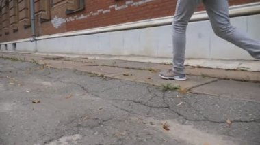 Young businessman in casual wear has business conversation by phone while going on urban street. Successful man with briefcase rushing to office and looking at his watch. Late to work. Slow motion.